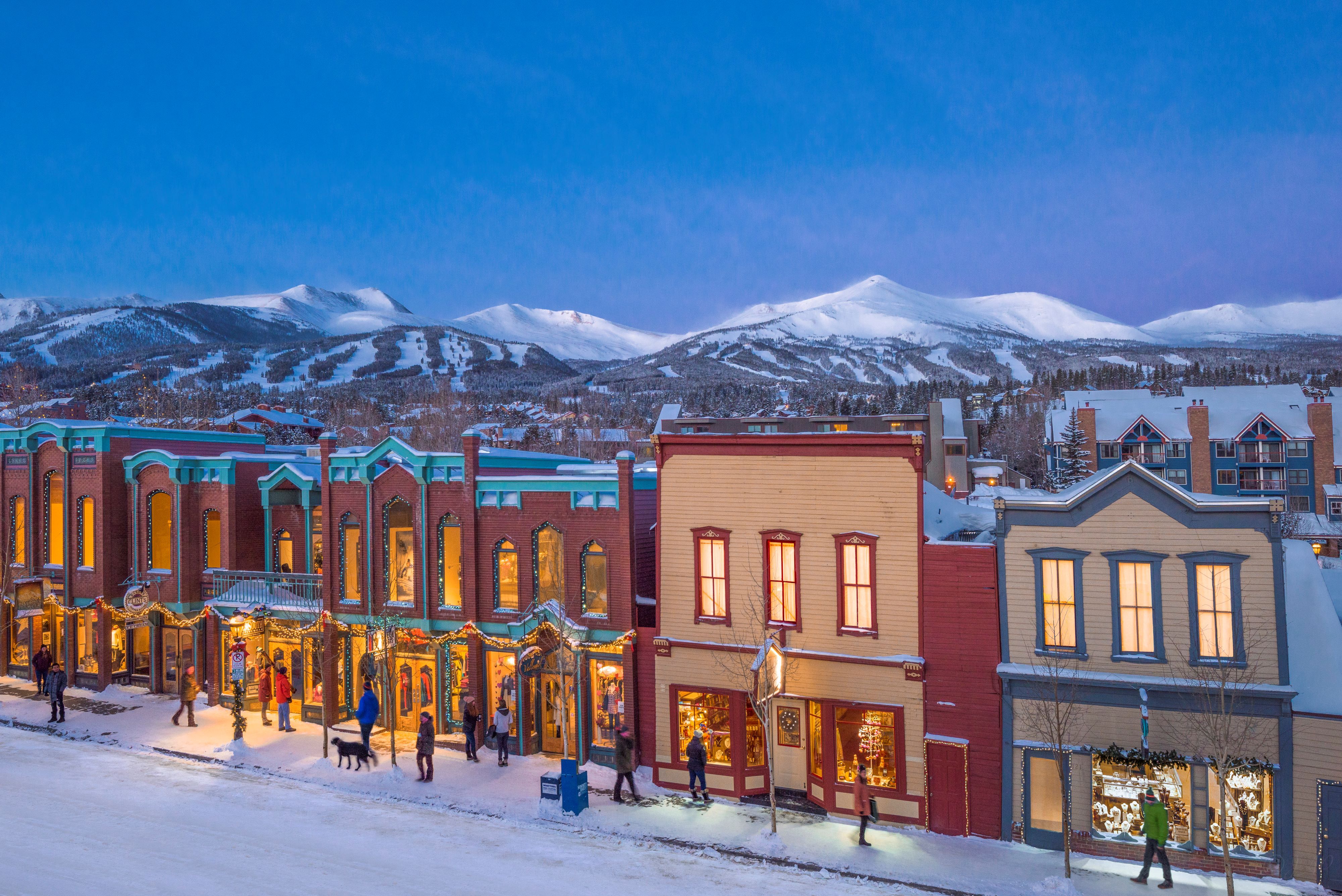 Snowy Main Street in Breckenridge with colorful storefronts and mountain peaks